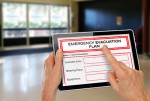 Hands with Computer Tablet and Emergency Evacuation Plan by Doors